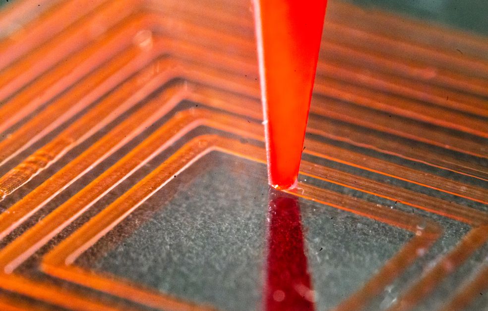 Närbild av en röd spets på en chip med kretsar i nyanser av orange och svart.