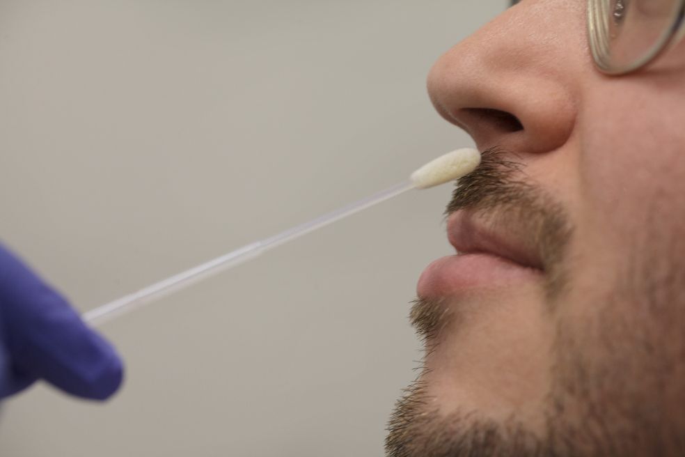 Testning med en bomullspinne i näsan på en man med glasögon.