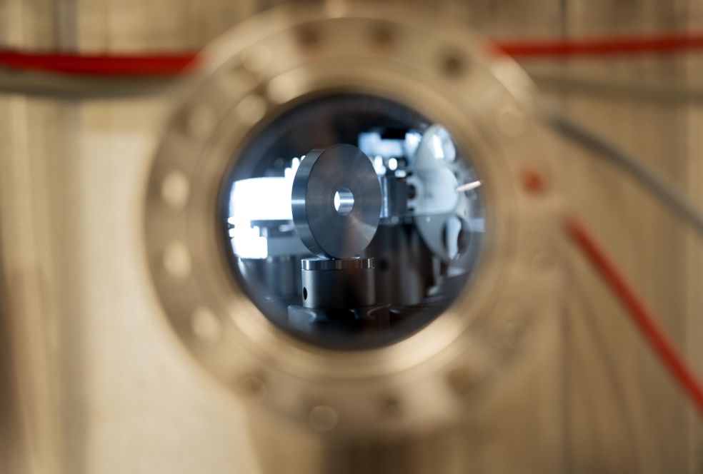 Tittar genom ett rör i en maskin, med metallkomponenter och ledningar synliga.