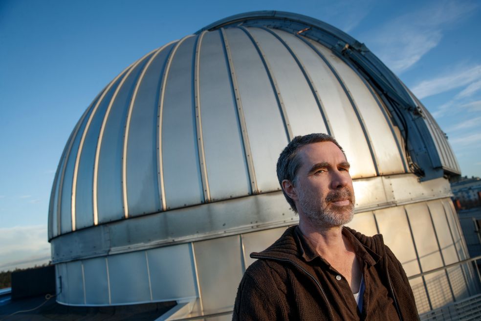 Man står framför en observatoriumkupol under en blå himmel.