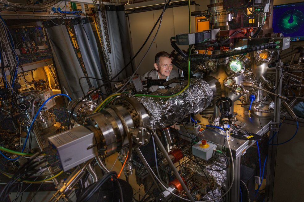 Forskare arbetar vid en komplex maskin omgiven av kablar och utrustning.