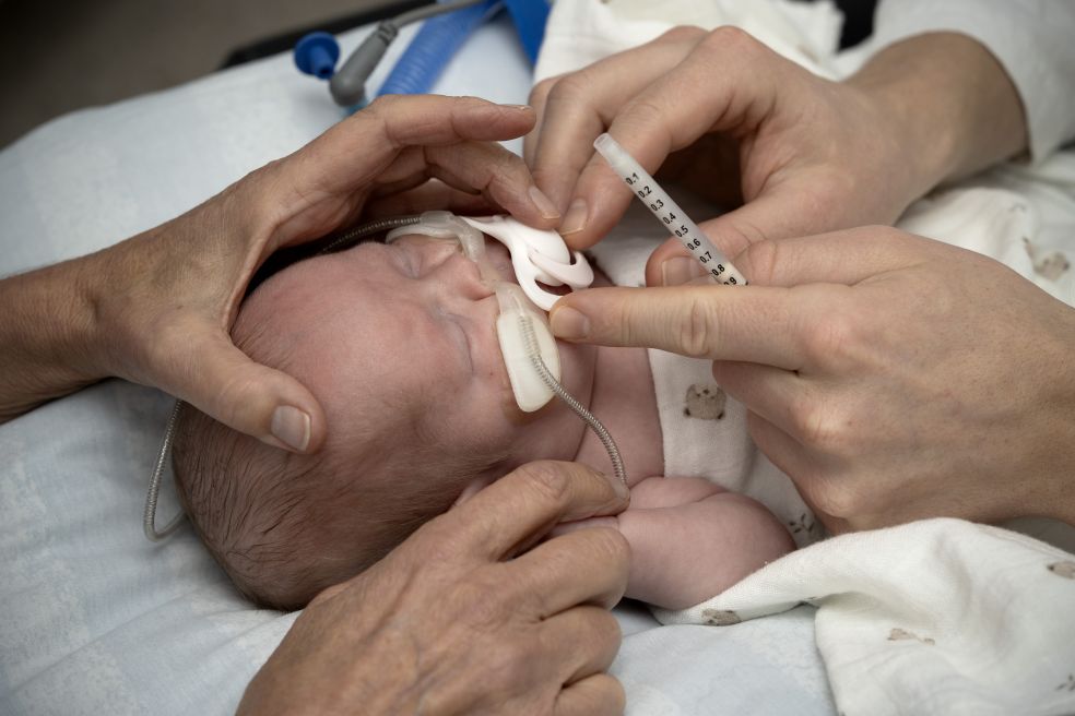 Händer som vårdar en spädbarn vid medicinsk behandling på ett sjukhus.