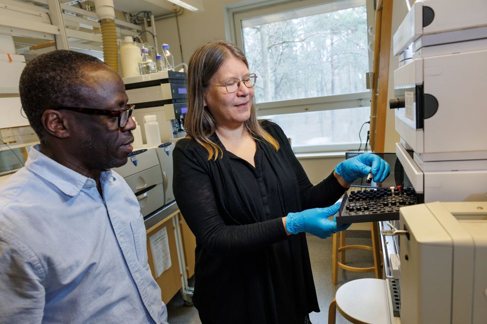 Två personer i ett laboratorium, en kvinna visar något på en apparat för en man.