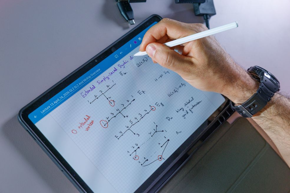 En hand skriver med en stylus på en surfplatta med anteckningar och diagram.