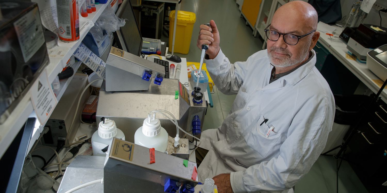 En man i labbrock arbetar med pipetter i ett laboratorium.