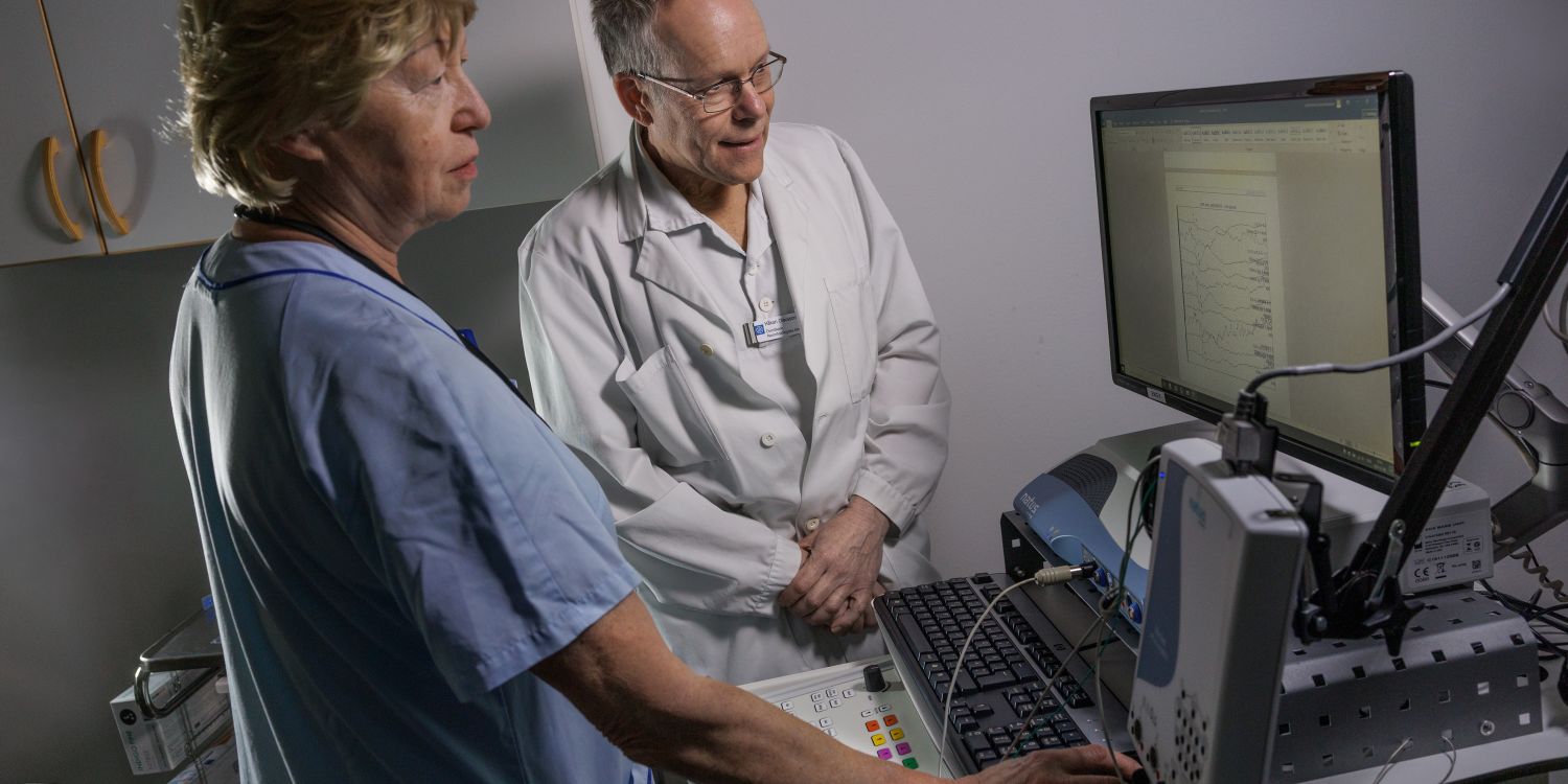 Två medicinska yrkespersoner vid en dator i ett undersökningsrum.