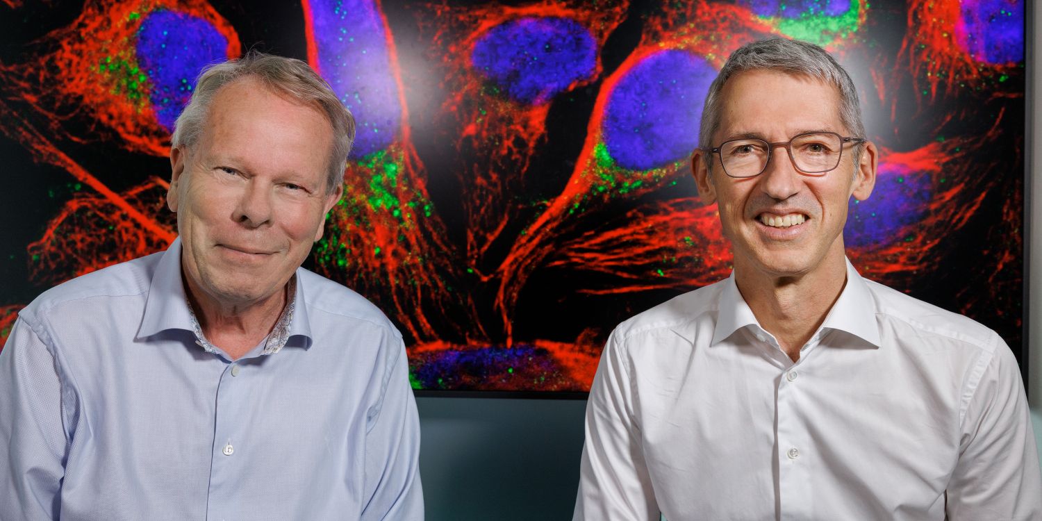 Mathias Uhlén och Jan Ellenberg framför en färgglad, mikroskopbild av celler.