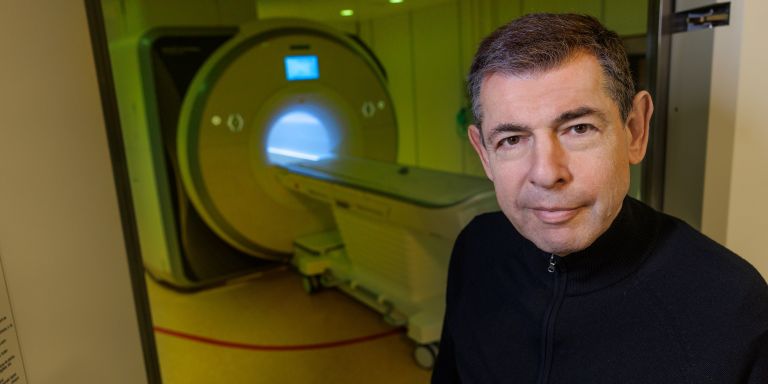 Man står framför en MRT-maskin i ett sjukhusrum.