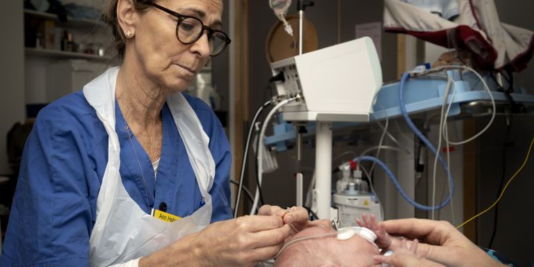 Sjuksköterska vårdar en nyfödd bebis i en sjukhusmiljö.