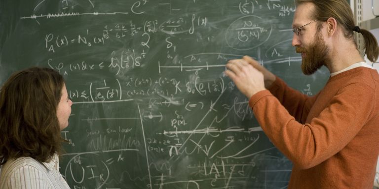 Personer framför griffeltavla med en massa matematiska formler