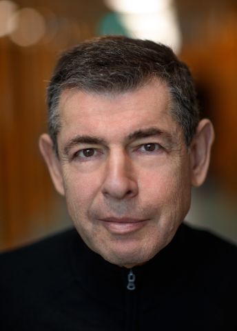 En medelålders man med kort grått hår och svart tröja, framför en suddig bakgrund.