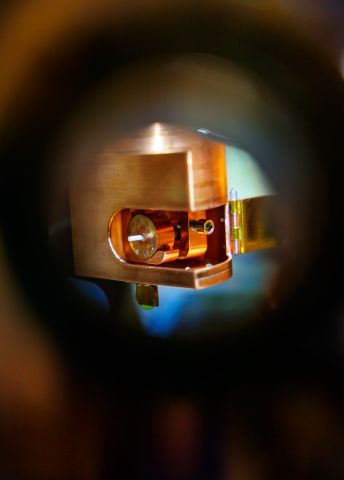 Närbild av en metallisk mekanism genom ett rör, med mjuka ljusreflexer.