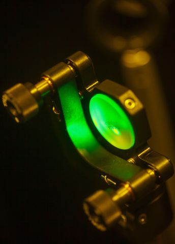 Grön lampa på en metallisk hållare mot en mörk bakgrund.