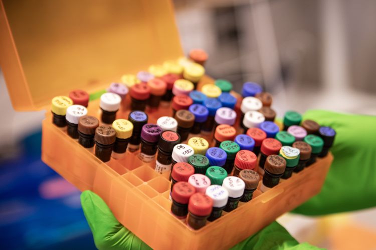 Två kvinnor i labbrockar samarbetar, ler och tittar på en färgglad låda.