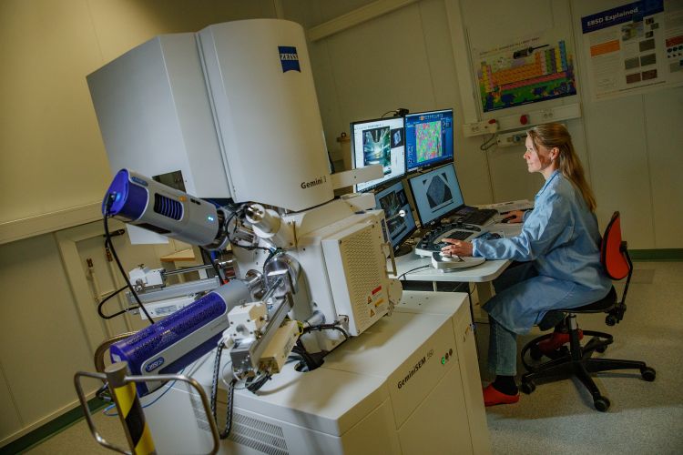 Kvinna vid dator som arbetar med avancerad laboratorieutrustning.