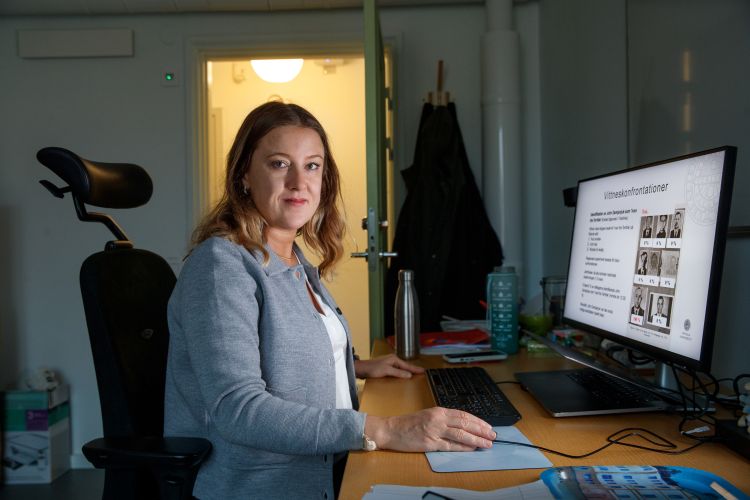 Kvinna sitter vid ett skrivbord med dator, ser fokuserad ut i ett kontor.