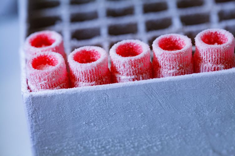 En man i labbrock arbetar med pipetter i ett laboratorium.