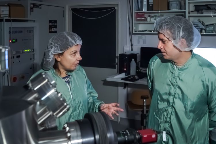 Två forskare i gröna labbrockar diskuterar i ett modernt laboratorium.