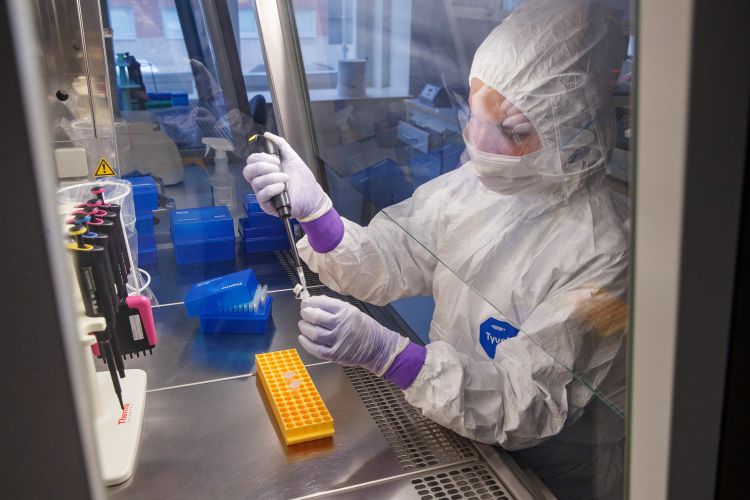 Forskare i skyddsdräkt använder en pipett i ett laboratorium.