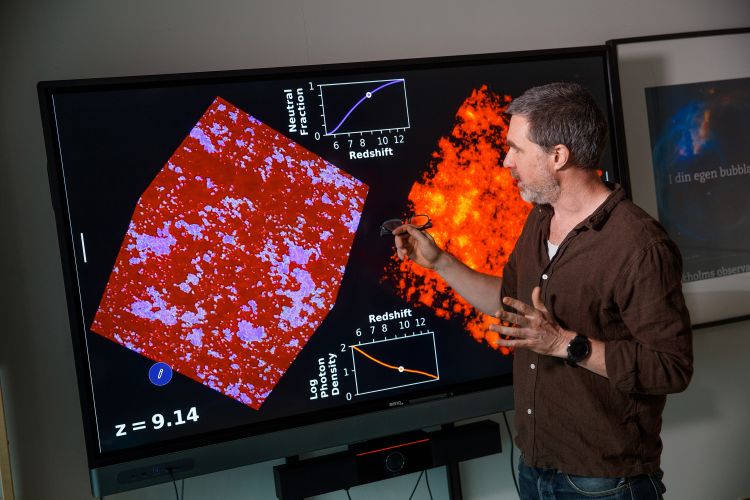 En man pekar på en stor skärm som visar röd och orange vetenskaplig data.