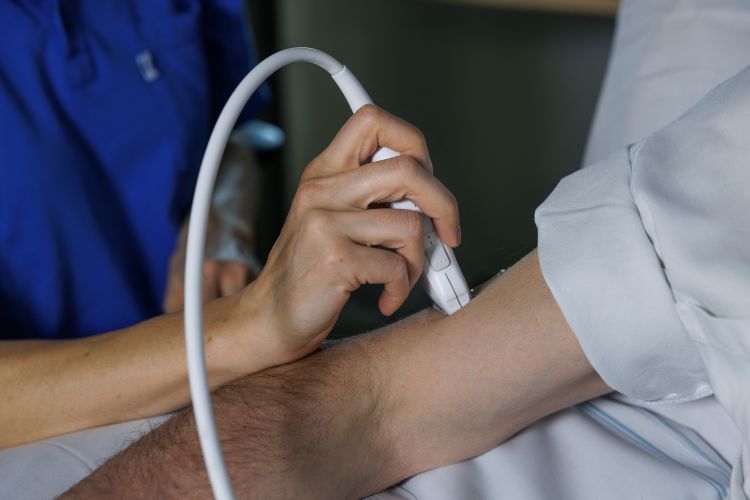 En sjukvårdspersonal undersöker en patients arm med en medicinsk apparat.