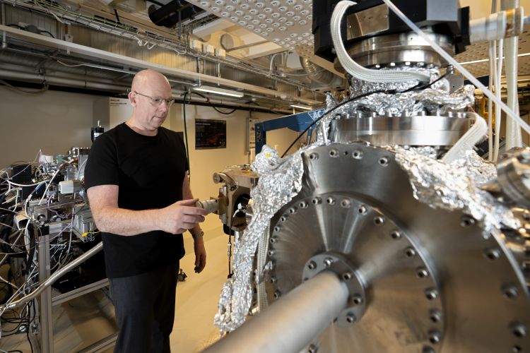 Forskare inspekterar en stor maskin i ett laboratorium, klädd i svart tröja.