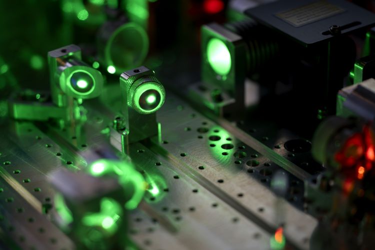 Gröna lasrar och optiska komponenter på en metallisk plattform.