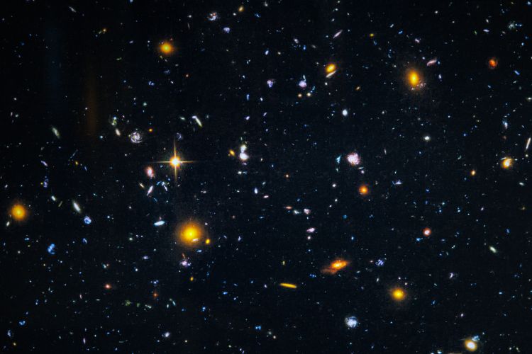 Stjärnspäckad nattbild med galaxer och ljusprickar mot en mörk bakgrund.