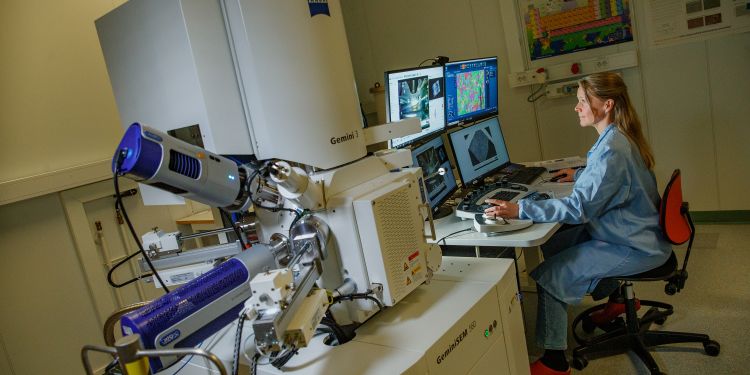 Kvinna vid dator som arbetar med avancerad laboratorieutrustning.