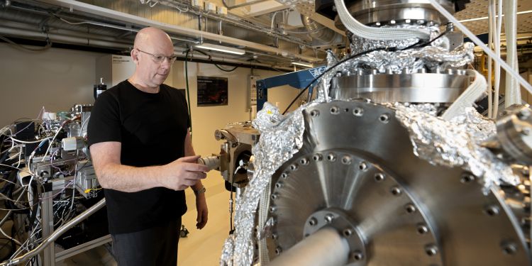 Forskare inspekterar en stor maskin i ett laboratorium, klädd i svart tröja.