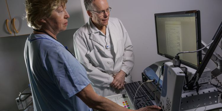 Två medicinska yrkespersoner vid en dator i ett undersökningsrum.