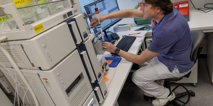 Laboratorieanställd arbetar vid avancerad utrustning med dator och instrument.