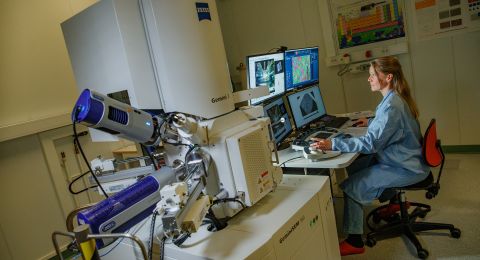 Kvinna vid dator som arbetar med avancerad laboratorieutrustning.