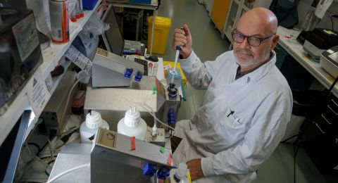 En man i labbrock arbetar med pipetter i ett laboratorium.