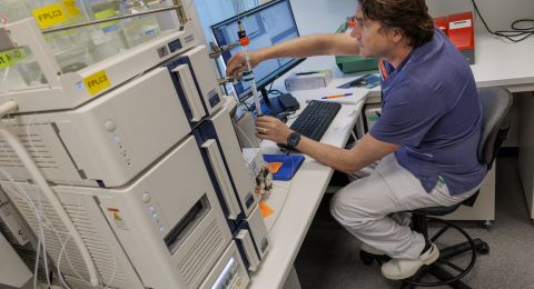 Laboratorieanställd arbetar vid avancerad utrustning med dator och instrument.